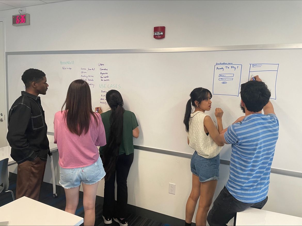 Students collaborating at whiteboard during UX design exercise